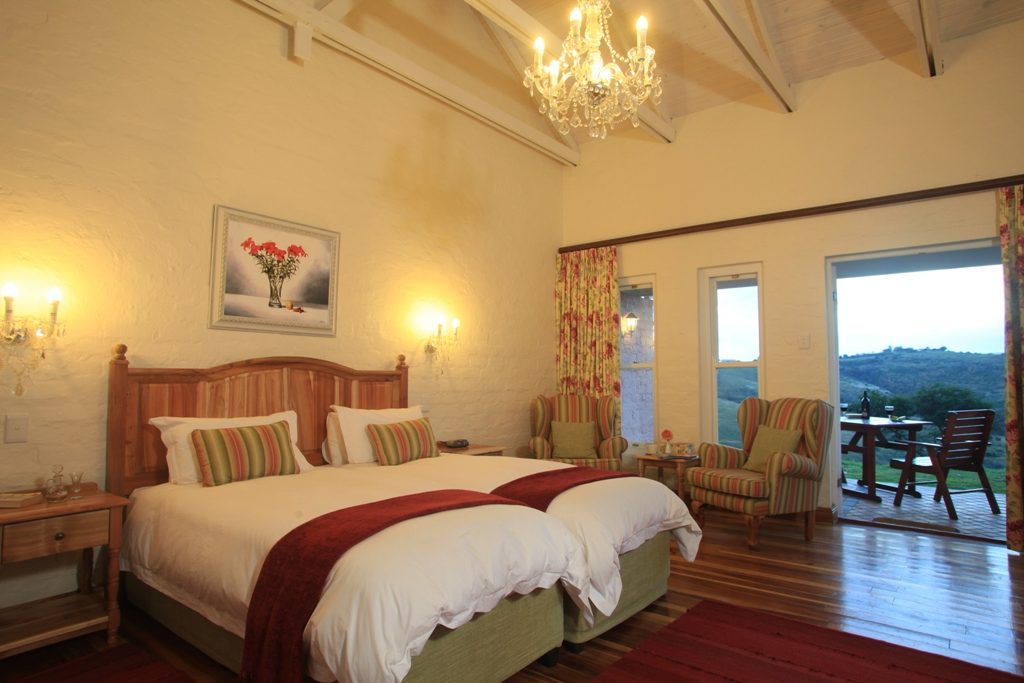A Village cottage bedroom with doors open to a patio and hillside view